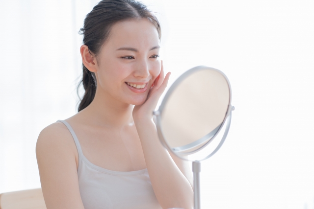 鏡を見て微笑む女性