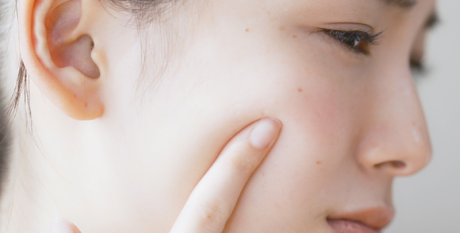 顔にできたシミを気にする女性